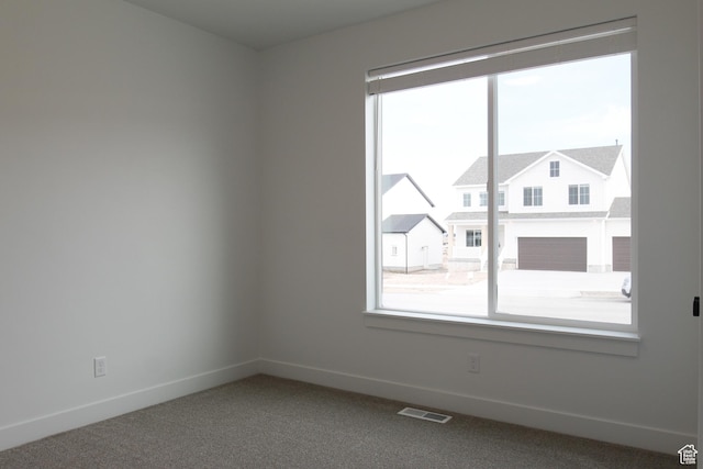 spare room with carpet, visible vents, and baseboards