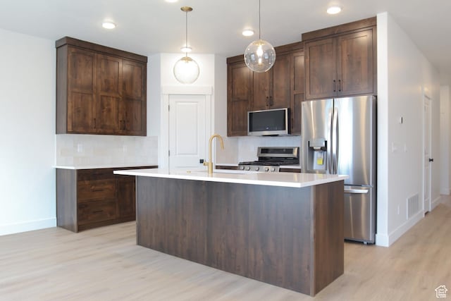 kitchen featuring a sink, stainless steel appliances, light wood-type flooring, baseboards, and tasteful backsplash