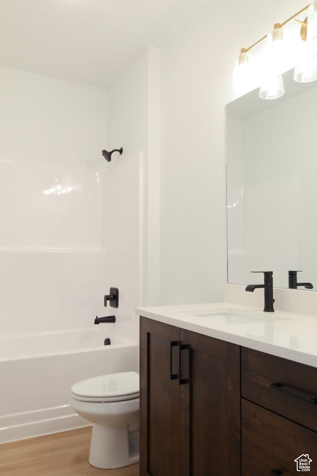 full bath featuring toilet, bathing tub / shower combination, wood finished floors, and vanity