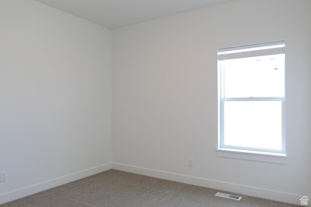 carpeted empty room featuring baseboards and visible vents