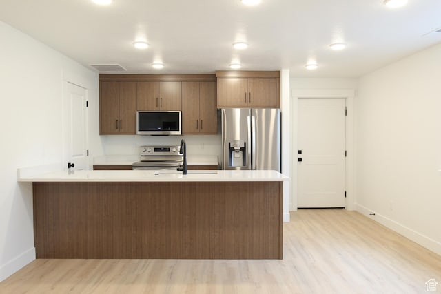 kitchen featuring baseboards, light wood-style floors, stainless steel appliances, and light countertops