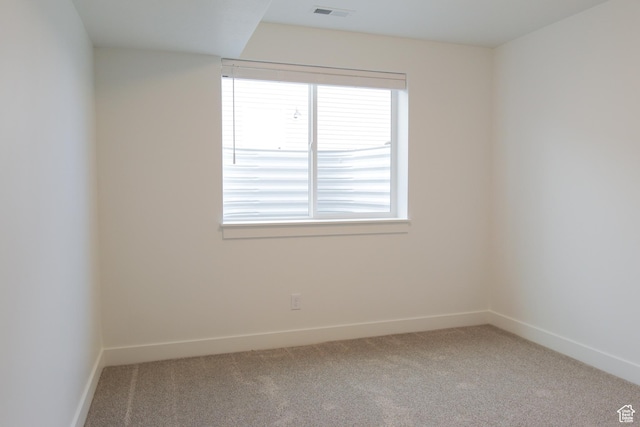 carpeted spare room featuring a wealth of natural light, visible vents, and baseboards