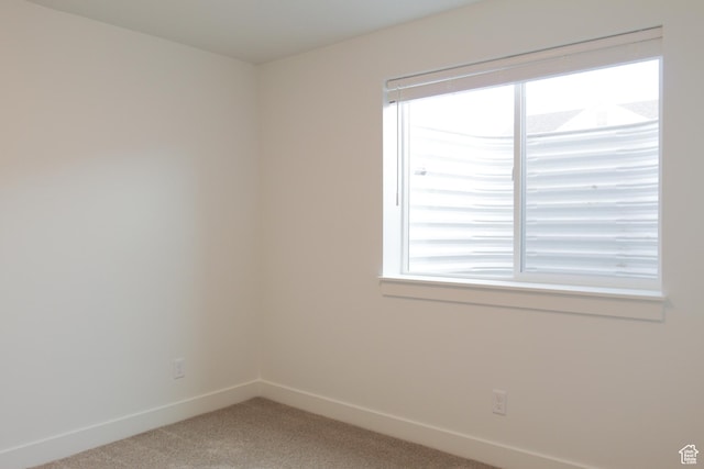 unfurnished room featuring light colored carpet, baseboards, and plenty of natural light