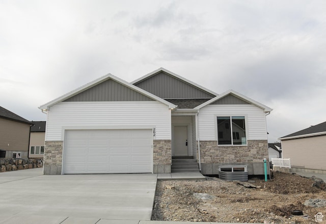 craftsman-style house with cooling unit, stone siding, and driveway