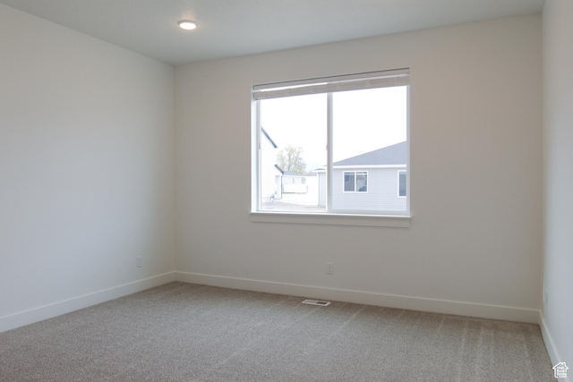 unfurnished room featuring light carpet and baseboards