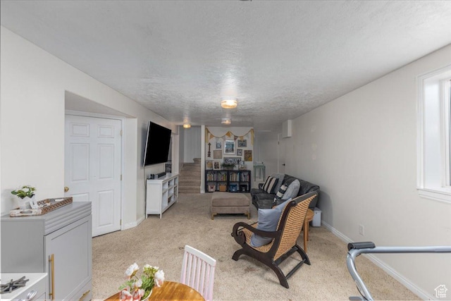 living area featuring light carpet, baseboards, and a textured ceiling