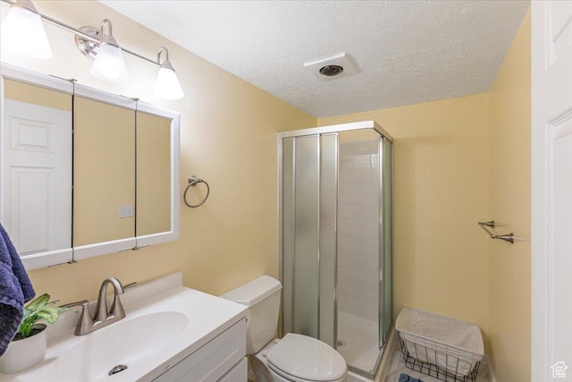 bathroom featuring a textured ceiling, toilet, a stall shower, and vanity