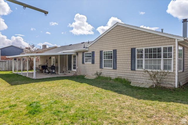 rear view of house with fence, a yard, and a patio