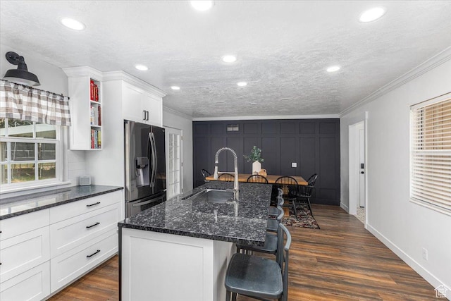 kitchen with white cabinets, crown molding, a breakfast bar, dark wood finished floors, and stainless steel refrigerator with ice dispenser