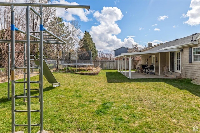 view of yard featuring a patio, a trampoline, a playground, and a fenced backyard