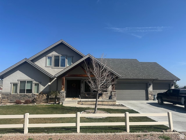 view of front facade featuring stone siding, a garage, and a fenced front yard