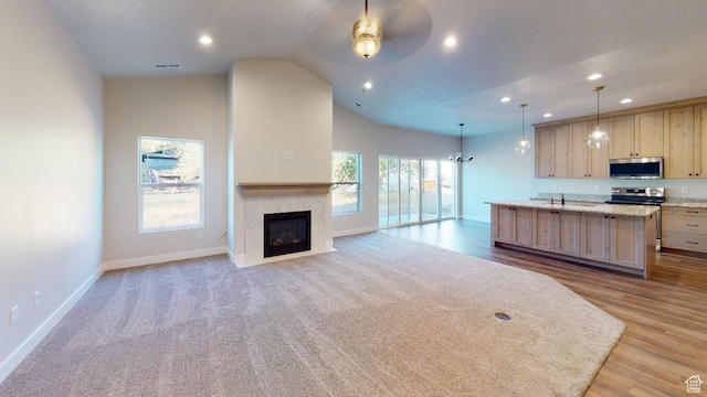 2696 W 2495 S Unit 207, Syracuse, UT 84075 - kitchen featuring open floor plan, lofted ceiling, a center island with sink, light brown cabinets, and appliances with stainless steel finishes