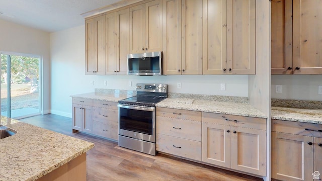 2696 W 2495 S Unit 207, Syracuse, UT 84075 - kitchen with light wood-type flooring, light brown cabinetry, baseboards, light stone countertops, and appliances with stainless steel finishes