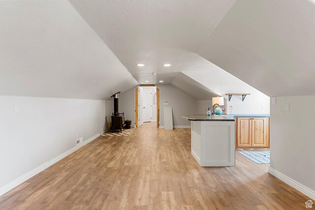 6832 W 1500 N, Cedar City, UT 84721 - additional living space featuring a wood stove, lofted ceiling, light wood-style flooring, baseboards, and visible vents