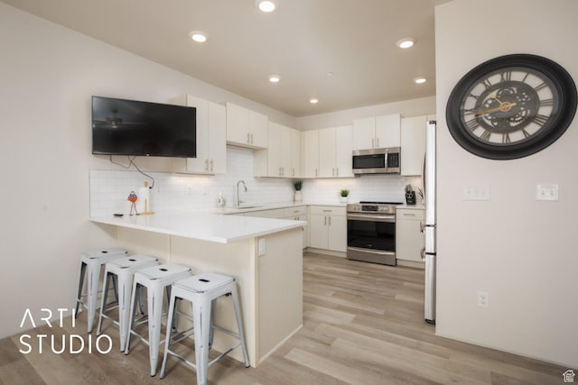 76 E 450 N, Ephraim, UT 84627 - kitchen featuring a peninsula, stainless steel appliances, a breakfast bar, and decorative backsplash