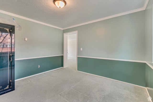 carpeted spare room with a textured ceiling, baseboards, and ornamental molding
