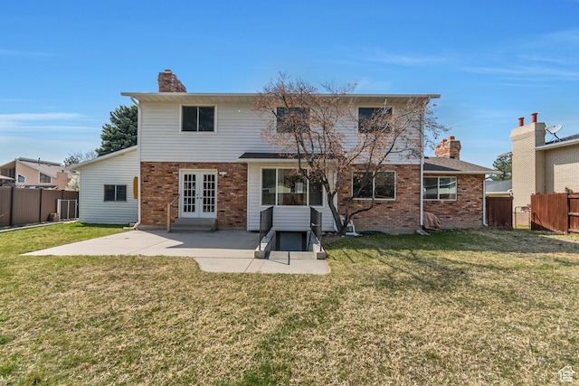 back of house with brick siding, french doors, a patio area, and a chimney