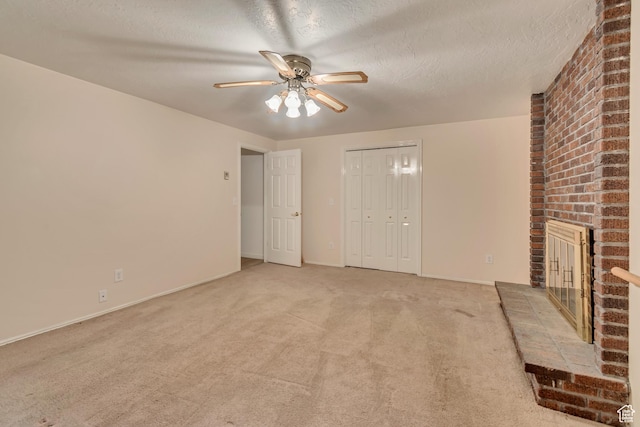 unfurnished living room with ceiling fan, a textured ceiling, light carpet, a brick fireplace, and baseboards