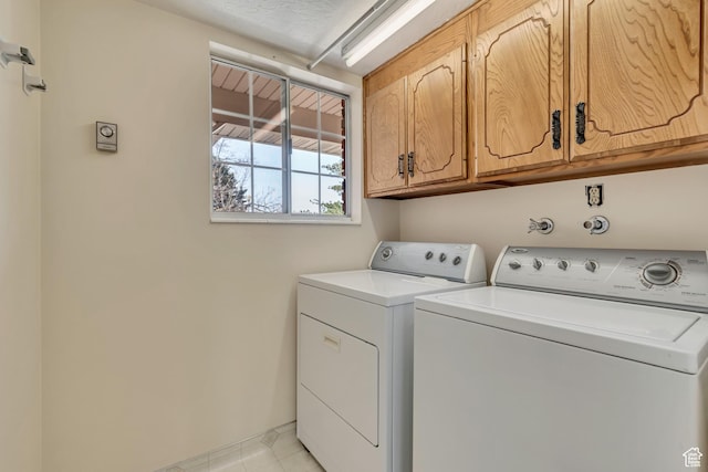 laundry area featuring cabinet space, light tile patterned floors, and independent washer and dryer