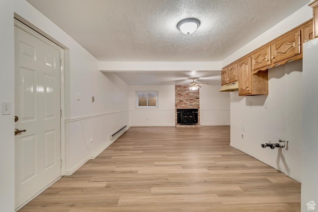 unfurnished living room with ceiling fan, light wood-type flooring, a baseboard heating unit, and a brick fireplace