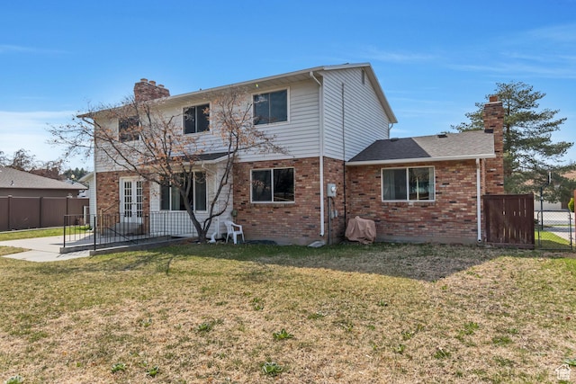 rear view of property featuring fence, brick siding, a chimney, and a lawn