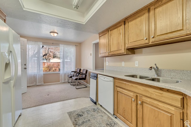 kitchen featuring baseboards, a sink, light countertops, white appliances, and light colored carpet