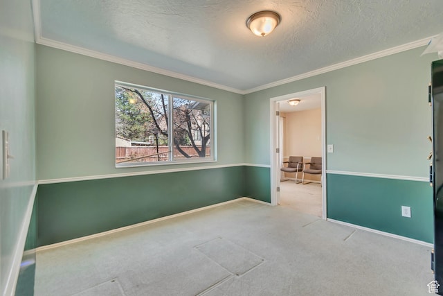 spare room featuring a textured ceiling, crown molding, baseboards, and carpet floors