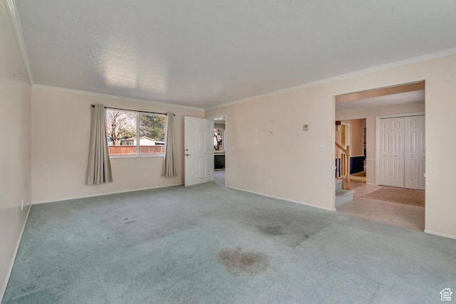 spare room featuring stairs, carpet, baseboards, and crown molding