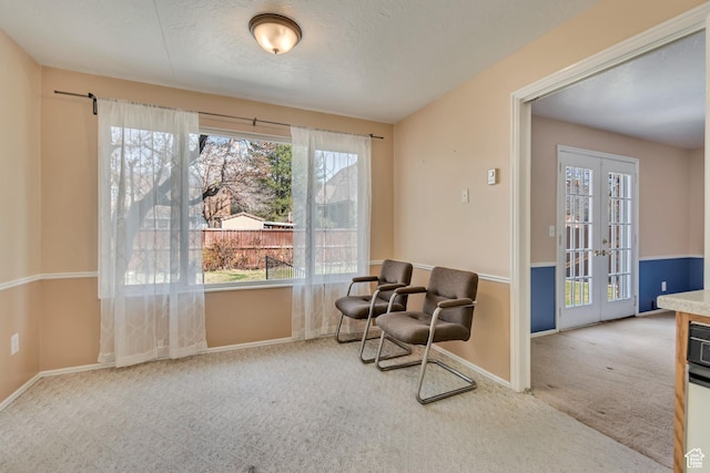 sitting room with a textured ceiling, french doors, baseboards, and carpet floors