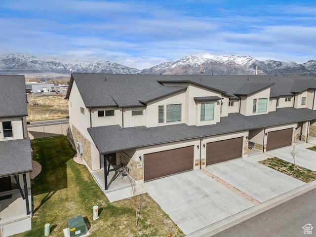 view of front of property featuring a mountain view, stone siding, a garage, and concrete driveway