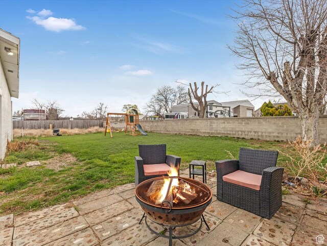 view of patio featuring a fenced backyard, a playground, and a fire pit