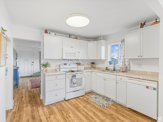 kitchen with white appliances, light countertops, light wood-style floors, and a sink