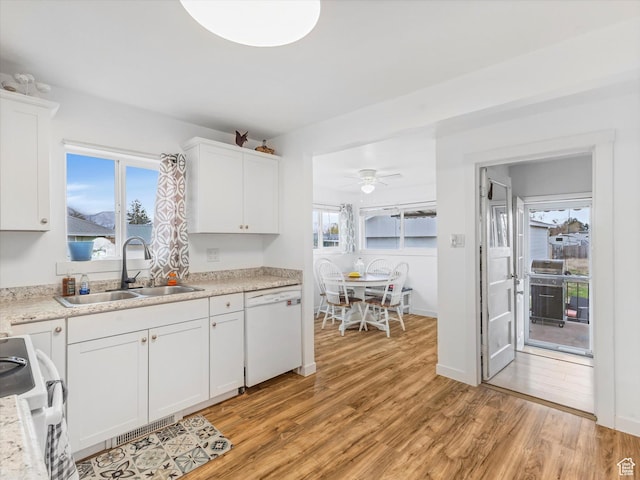 kitchen with light countertops, a sink, dishwasher, light wood-type flooring, and white cabinets