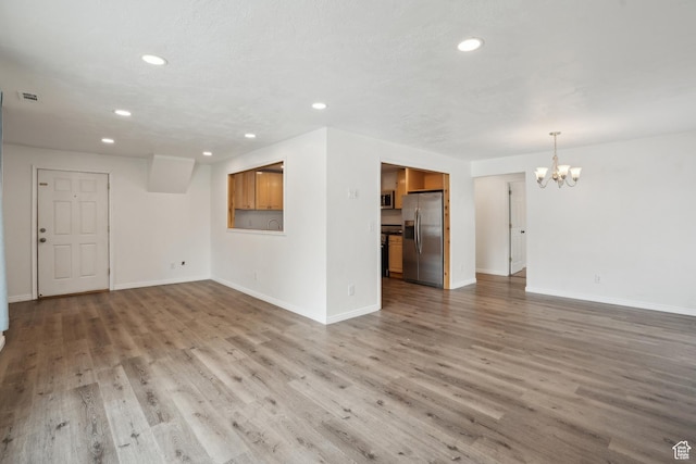 148 N Center St, Midway, UT 84049 - unfurnished living room with baseboards, wood finished floors, recessed lighting, and a notable chandelier