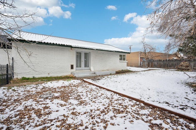 148 N Center St, Midway, UT 84049 - snow covered back of property featuring french doors, brick siding, fence, and metal roof