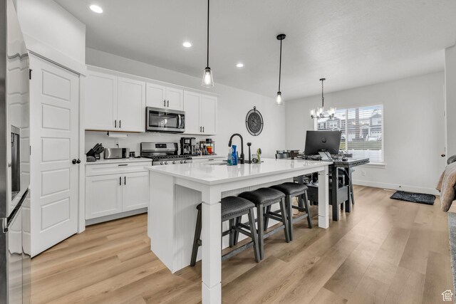 16132 S Coupler Ln Unit 406, Bluffdale, UT 84065 - kitchen featuring an island with sink, light wood-type flooring, a sink, and stainless steel appliances