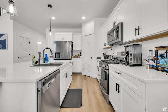 16132 S Coupler Ln Unit 406, Bluffdale, UT 84065 - kitchen with appliances with stainless steel finishes, white cabinetry, a sink, light wood-style floors, and hanging light fixtures