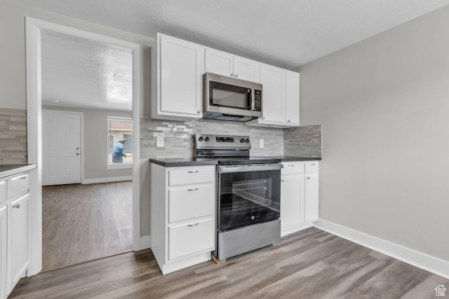 2620 S 8590 W, Magna, UT 84044 - kitchen featuring backsplash, white cabinetry, appliances with stainless steel finishes, and light wood-style floors
