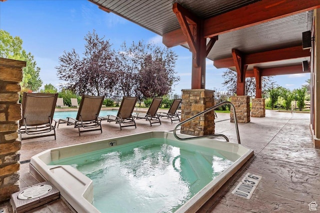 pool with an outdoor hot tub and a patio area
