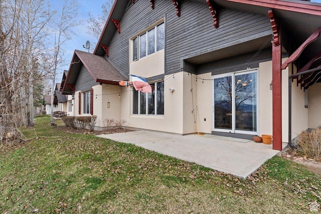 back of property featuring stucco siding, a patio area, and a yard