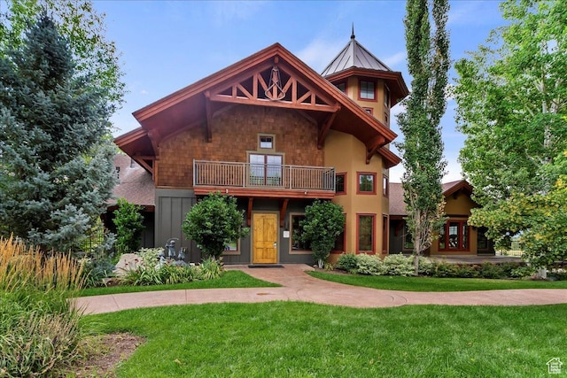 view of front of house featuring a balcony and a front lawn
