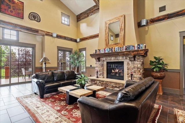 living room with a stone fireplace, high vaulted ceiling, baseboards, and visible vents