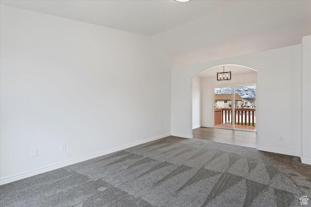 empty room with arched walkways, carpet, and baseboards