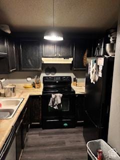 1450 N Sagewood Rd E Unit 17, Price, UT 84501 - kitchen with light countertops, under cabinet range hood, black appliances, dark cabinets, and dark wood-type flooring