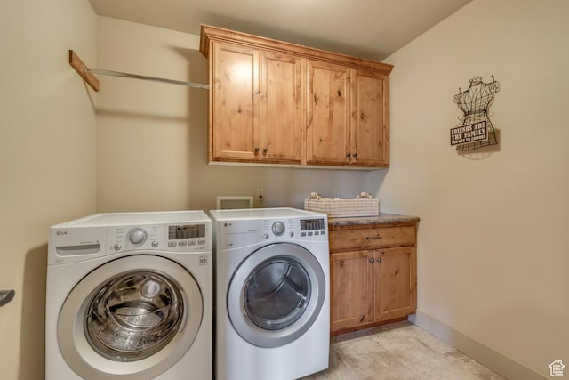 washroom with baseboards, washer and dryer, and cabinet space