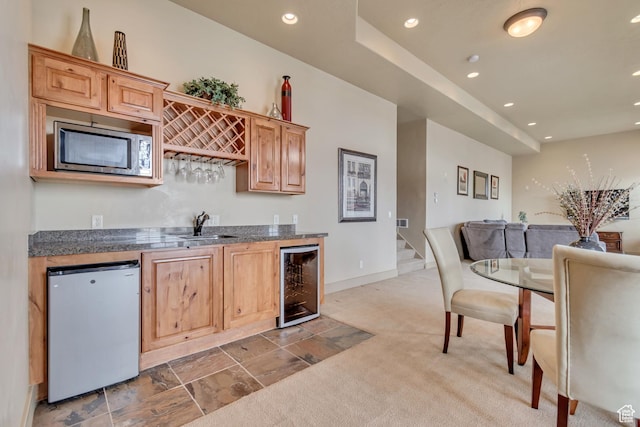 kitchen featuring wine cooler, a sink, refrigerator, stainless steel microwave, and recessed lighting