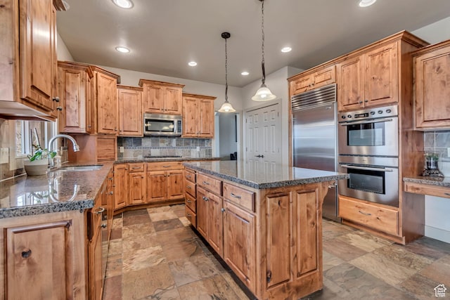 kitchen featuring stainless steel appliances, a center island, dark stone counters, backsplash, and a sink