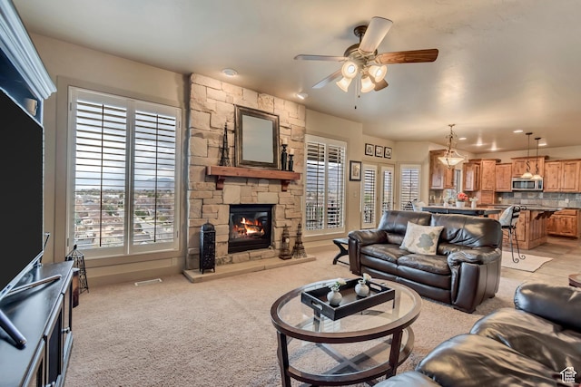 living area featuring light carpet, a fireplace, visible vents, and a ceiling fan
