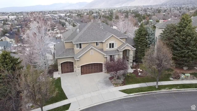 view of front facade with driveway, stone siding, stucco siding, a residential view, and a garage