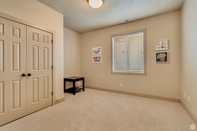 unfurnished bedroom featuring a closet, a textured ceiling, baseboards, and carpet